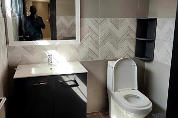 Le sanitaire refait : meuble suspendu, miroir rétroéclairé, faïence à chevrons.